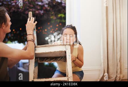 Le restaurer à sa gloire passée. Une jeune femme sablant une chaise ancienne. Banque D'Images