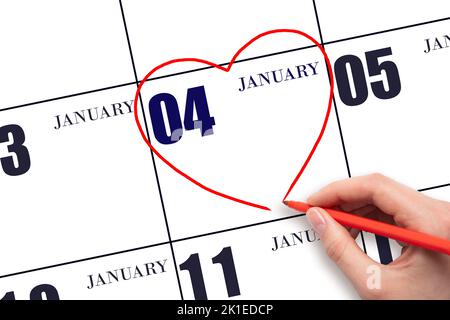 4th jour de janvier. Une main de femme dessinant un coeur rouge à la date du calendrier du 4 janvier. Le coeur comme symbole de l'amour. Mois d'hiver. Le jour du vous Banque D'Images