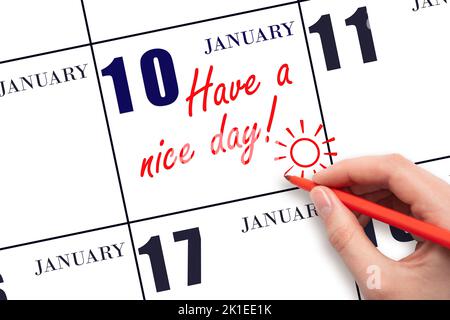 10th jour de janvier. La main écrivant le texte ont une belle journée et dessinant le soleil sur la date calendrier 10 janvier. Enregistrez la date. Mois d'hiver, jour o Banque D'Images