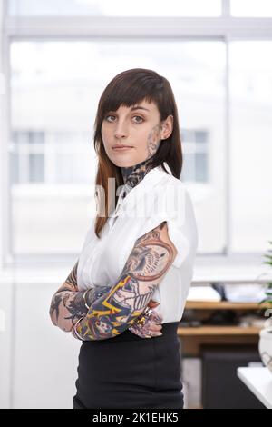 Des shes prêts à faire du rock sur la scène de l'entreprise. Une jeune femme d'affaires couverte de tatouage dans son bureau. Banque D'Images