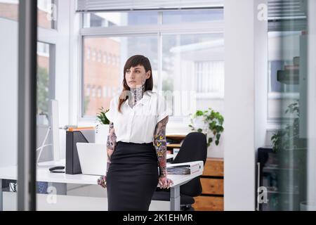 Des shes prêts à faire du rock sur la scène de l'entreprise. Une jeune femme d'affaires couverte de tatouage dans son bureau. Banque D'Images