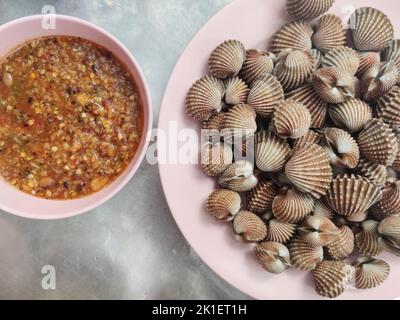 Tegillarca granosa ou aussi connu sous le nom de coq , mye de sang. Gros plan. Après cuisson. Avec sauce thaï épicée aux fruits de mer. Cuisine populaire thaïlandaise locale. Banque D'Images