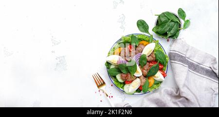 Salade Périgord avec foie de poulet, tomates, concombres, œufs, laitue et épinards. Arrière-plan blanc de la table de cuisine, bannière vue du dessus Banque D'Images