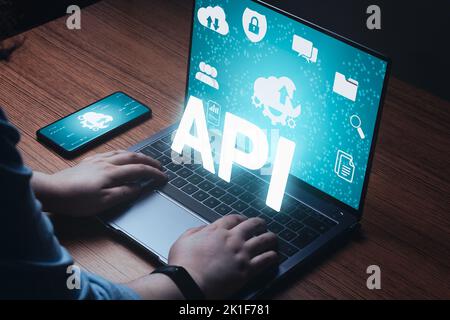 Woman use laptop with API word on VR screen and multimedia icons. Internet and technology concept. Business, programming, interface. Stock Photo