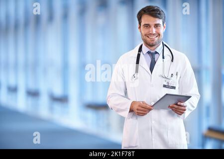 Nous sommes heureux de vous aider. Portrait d'un jeune médecin heureux debout dans un couloir d'hôpital avec un dossier de patients Banque D'Images