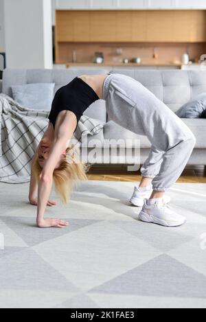 La femme effectue un exercice de pont à la maison Banque D'Images