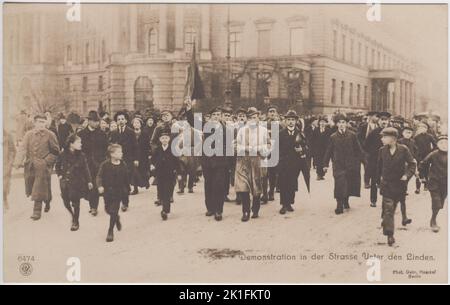 Démonstration dans la rue der Straße Unter den Linden / démonstration à Berlin sur la rue Unter den Linden lors de la révolution allemande de novembre 1918. Une foule d'hommes, de femmes et d'enfants marche au milieu de la rue. Certains hommes sont en uniforme militaire, y compris un marin qui porte un drapeau rouge. La photographie a été vendue comme carte postale par carte postale par Gebr. Haeckel, Berlin. Banque D'Images