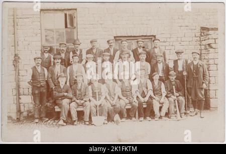 Groupe de naves édouardiens photographiés dans des vêtements de travail (y compris une gamme de chapeaux). Plusieurs hommes tiennent des outils, y compris une bêche et une hache Banque D'Images