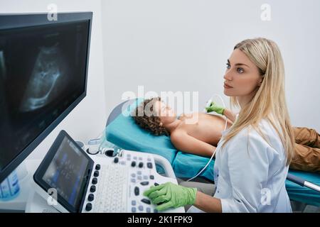 Échographie cardiaque chez un enfant de sexe masculin avec un spécialiste de l'échographie pendant un examen médical en pédiatrie Banque D'Images