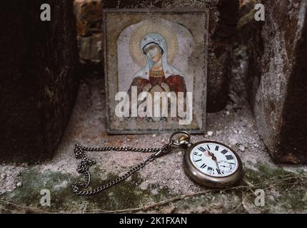 Montre de poche antique avec chalet, située par l'icône abandonnée de Virhin Marie dans une cathédrale catholique en ruines Banque D'Images