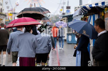 18 septembre 2022, Bavière, Munich : les visiteurs de l'Oktoberfest se promornent sur le terrain avec des parasols. Photo: Sven Hoppe/dpa Banque D'Images