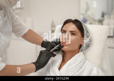Le cosmétologue fait des injections pour augmenter les lèvres et les anti-rides de la femme dans le salon de beauté Banque D'Images