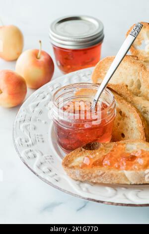 Pots de gelée de pomme de crabe avec un peu sur une tranche de pain de levain grillé Banque D'Images