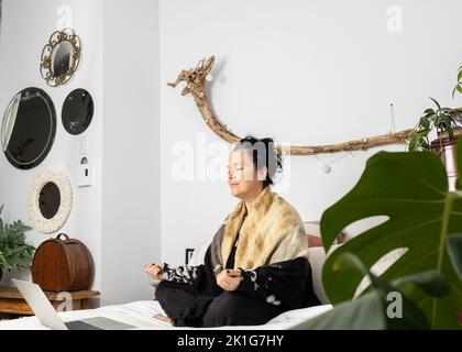 Une femme d'âge Middled méditant assise sur son lit perdue dans ses pensées. Photo de haute qualité Banque D'Images