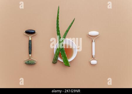 Rouleau de massage facial à jade vert et blanc avec aloès et miel. Produits de massage anti-âge naturels pour le drainage lymphatique et le lissage des rides Banque D'Images