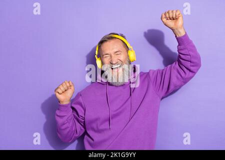 Portrait de beau retraité positif homme violet casque à capuche shout oui yeux fermés mains vers le haut isolé sur fond violet couleur Banque D'Images