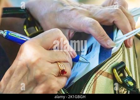 Une photo avec les mains d'une vieille femme qui écrit sur un morceau de papier Banque D'Images