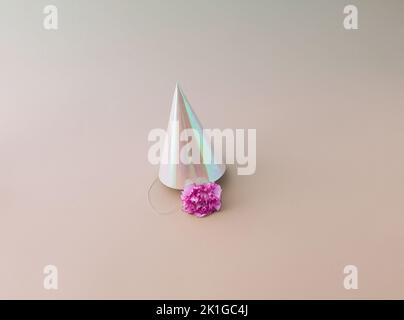 A party hat with a pink flower underneath, on a pink background. Minimal concept. Stock Photo