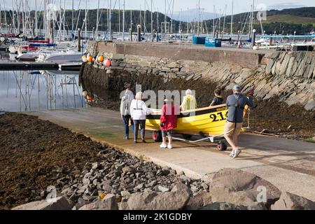 Club d'aviron de l'île de Bute avec leur skiff de St Ayles (conception écossaise), Bruchag se prépare à mettre dans l'eau à Rhu Marina pour la côte Rowin Banque D'Images