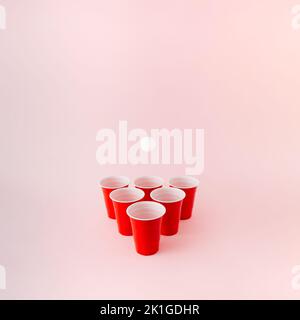 Six red plastic beer pong cups with white ball hovering above. Stock Photo