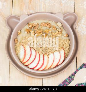 Porridge à grains entiers végétaliens. Délicieux repas plein de glucides. Tranches de pomme, noix. Des mets sucrés savoureux pour les enfants. Petit déjeuner traditionnel. Banque D'Images