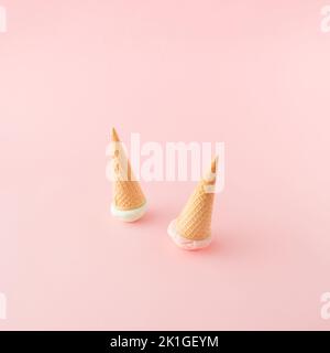 Two ice cream cones with green and pink scoops turned upside down on pink background. Top view. Minimal concept. Banque D'Images