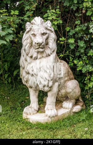 Statue de lion blanc ornementale dans un jardin intérieur avec feuillage vert derrière, Royaume-Uni Banque D'Images