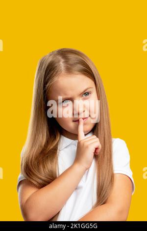 Enfant pensif. Solution au problème. Décision difficile. Portrait de la petite fille pensive troublée considérant l'option isolée sur orange vide espace backgroun Banque D'Images