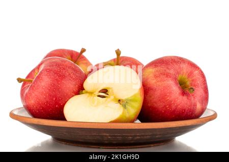 Quatre pommes rouges entières et une moitié juteuses sur une plaque d'argile, macro, isolées sur fond blanc. Banque D'Images
