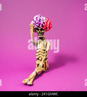 Halloween skeleton with fully bloomed flowers hairstyle on pink background. Minimal concept. Stock Photo