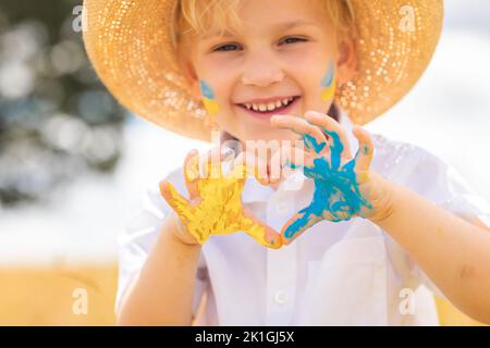 Arrêtez la guerre en Ukraine. Un garçon ukrainien avec drapeau ukrainien - jaune et bleu peint sur les mains se tient contre la guerre. Banque D'Images