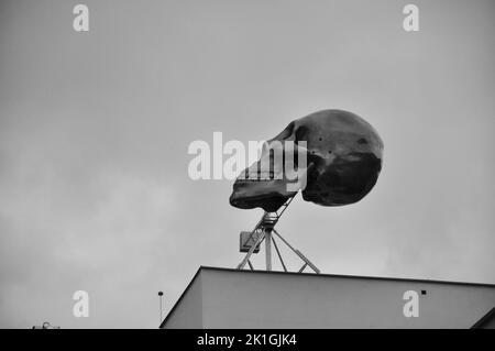 Gros plan en échelle de gris, photo sous angle d'une installation d'art du crâne géant au sommet d'un bâtiment à Prague, en République tchèque Banque D'Images