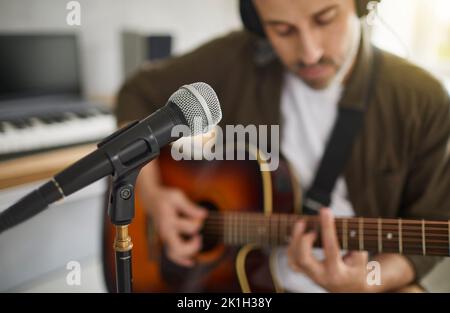 Musicien jouant sa guitare et chantant dans un microphone dans un studio d'enregistrement moderne Banque D'Images