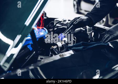 Homme travailleur dans un studio de nettoyage de voiture ou de nettoyage de voiture nettoie un engin de voiture Banque D'Images