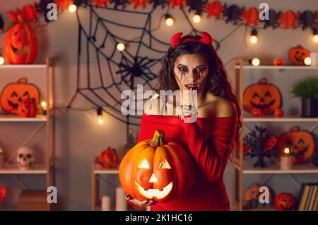 Femme déguisée comme diable faisant le doigt de Shh sur le geste de lèvre à la fête secrète d'Halloween Banque D'Images