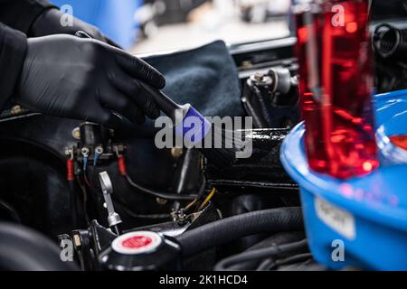 Homme travailleur dans un studio de nettoyage de voiture ou de nettoyage de voiture nettoie un engin de voiture Banque D'Images