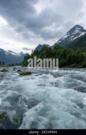 Paysages merveilleux en Norvège. Vestland. Magnifique paysage de la cascade de Laukifossen et de la rivière Oldeelva à Olden. Montagnes et arbres neigés à l'arrière-plan Banque D'Images