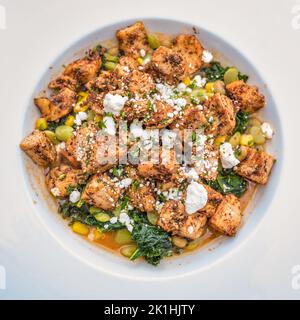 plat de poulet sauté recouvert de feta et accompagné d'épinards sautés dans un bol de service blanc Banque D'Images