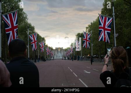 Les drapeaux de l'Union bordent le Mall en direction de Buckingham Palace, alors que les gens se mettent à attendre la nuit pour les funérailles de la Reine le lendemain, Londres, Royaume-Uni Banque D'Images