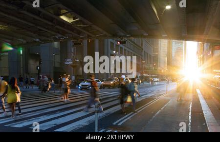 La lumière du soleil brille sur les gens qui se promonvent dans une rue animée en traversant une rue en face à Grand Central Station à Manhattan New York City NYC Banque D'Images