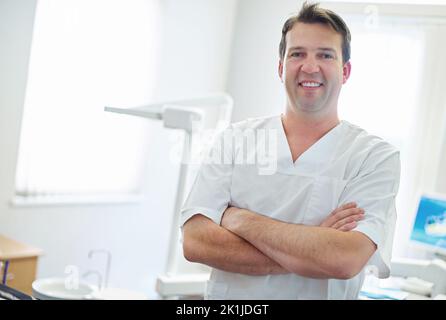 Vos dents sont superbes. Portrait d'un dentiste debout près de l'équipement dentaire dans son bureau Banque D'Images