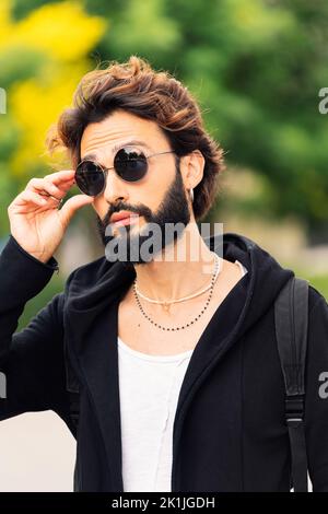 jeune homme élégant avec barbe en train de mettre des lunettes de soleil Banque D'Images