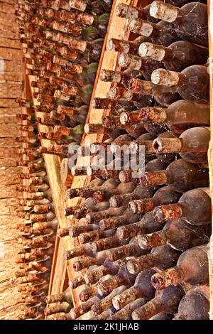 Ancienne cave à vin avec poutres en bois et des dizaines de vieilles bouteilles de vin poussiéreuses, mûrissement paisiblement dans une cave quelque part dans l'île de Zakynthos, en Grèce. Banque D'Images