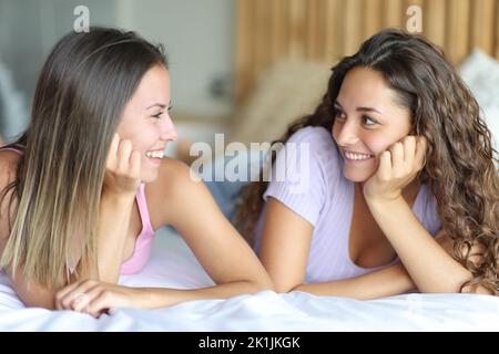Deux femmes heureuses se regardant l'une l'autre sur un lit dans la chambre Banque D'Images
