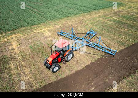 Une grande machine agricole cultive la terre. La vue du dessus. Labourage de terres pour la plantation de cultures. Photos de la vue de l'oiseau avec un quadc Banque D'Images