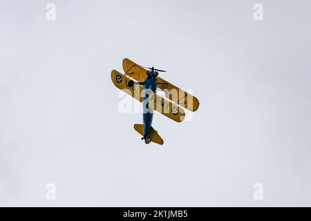 Vue à angle bas d'un avion bicolore vintage de la US Navy qui effectue des acrobaties aériennes dans le ciel gris Banque D'Images