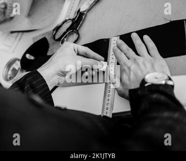 couturière lieu de travail. homme couturière crée un motif avec de la craie sur le tissu pour coudre des vêtements en studio sur mesure. Banque D'Images