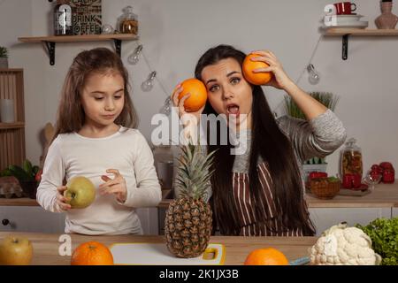 Mère et sa fille font une coupe de fruits et s'amusent dans la cuisine. Banque D'Images
