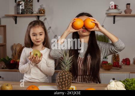 Mère et sa fille font une coupe de fruits et s'amusent dans la cuisine. Banque D'Images