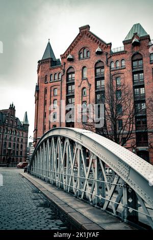 Un pont voûté sur les canaux d'Alster avec la route pavée avec des bâtiments en briques rouges en arrière-plan Banque D'Images